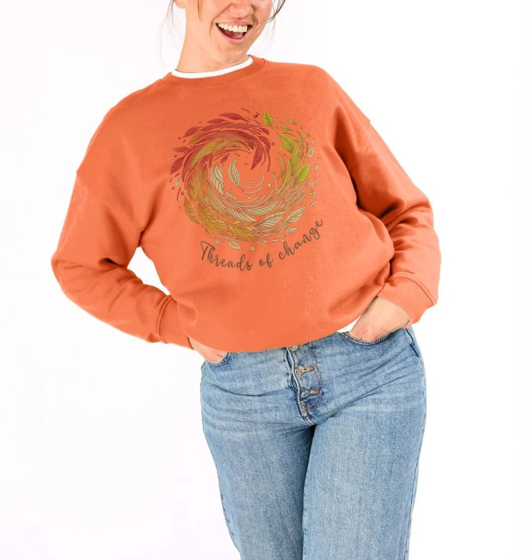 a woman models an orange oversized sweatshirt with "threads of change" printed on it, highlighting sustainable fashion.
