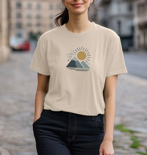 A woman wearing a Twin Peaks Sunrise organic t-shirt featuring a design of mountains and a sun.