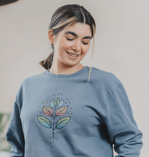 A woman in a blue sweatshirt featuring a colorful plant design