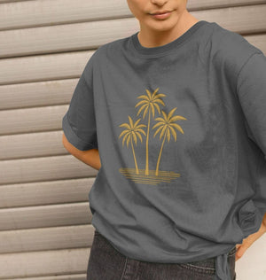 A woman in a gray t-shirt featuring a gold palm tree design, showcasing the Island Palms Women's Relaxed Fit style.