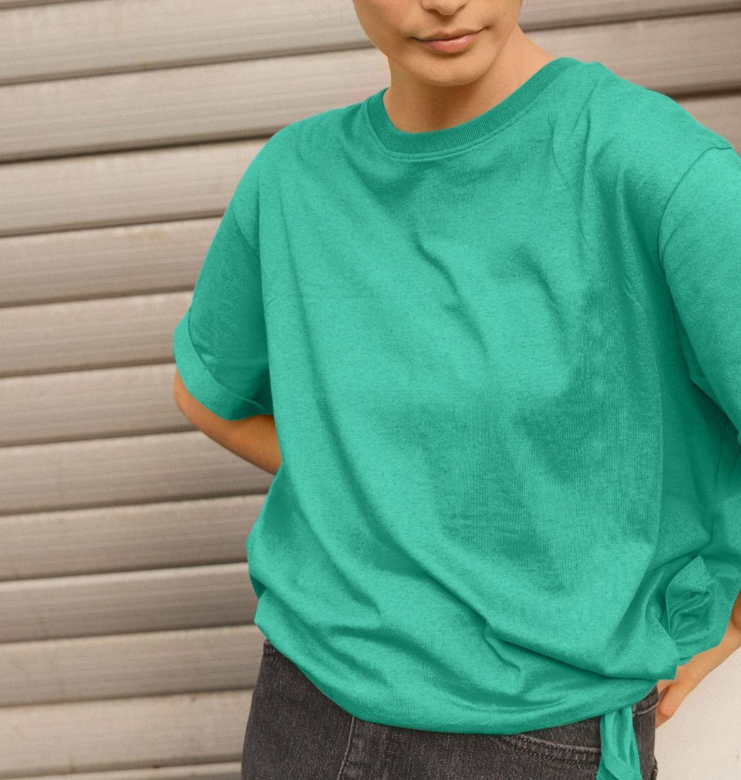 A woman in a green ReSprout relaxed fit t-shirt and jeans stands confidently, showcasing a casual and stylish look.