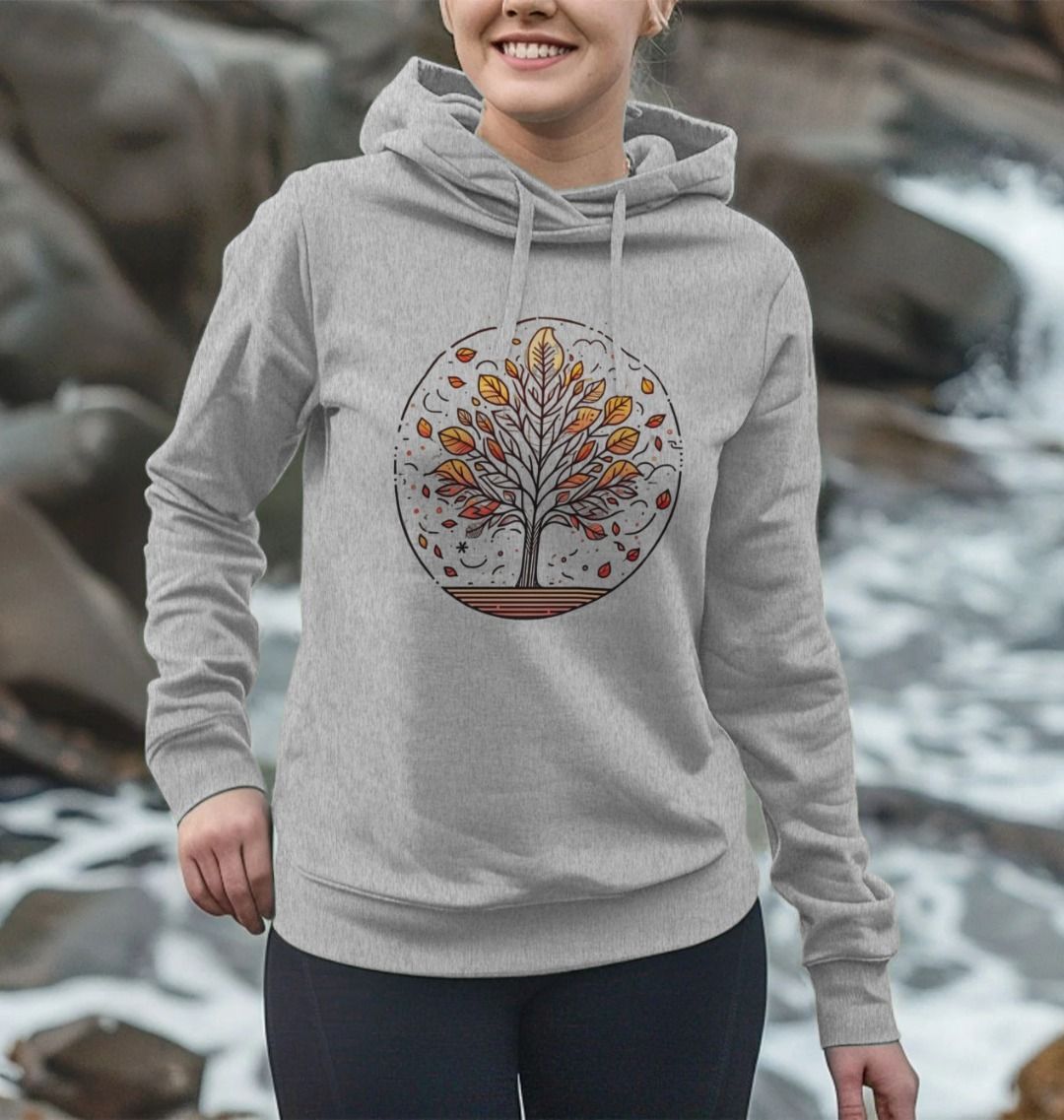 A woman in a grey hoodie featuring an autumn tree design, showcasing the Inner Peace Women's Pullover Organic Hoodie.