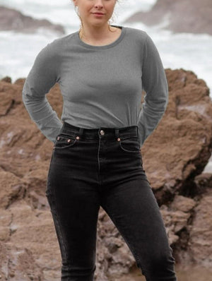 A woman in a grey long sleeve shirt and black jeans, showcasing a stylish and casual outfit.