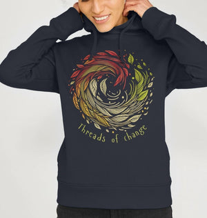 A woman in a hoodie that reads "Threads of Change," showcasing a stylish and eco-friendly fashion choice.
