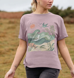 A woman in a purple t-shirt featuring a bird and waves, showcasing the golden horizon women's relaxed fit design.