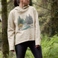 A woman in a relaxed fit hoodie featuring a serene forest scene
