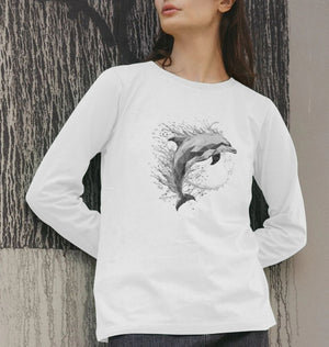 A woman in a white long sleeve shirt featuring a dolphin design, showcasing the ocean prism women's organic t-shirt.