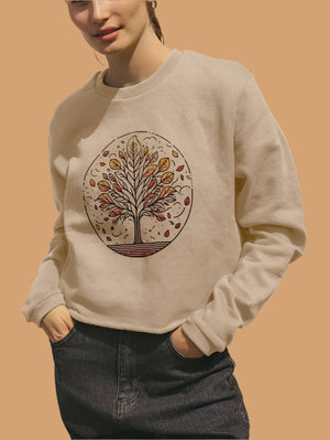 A woman models a boxy fit organic sweater featuring a colorful autumn tree design.