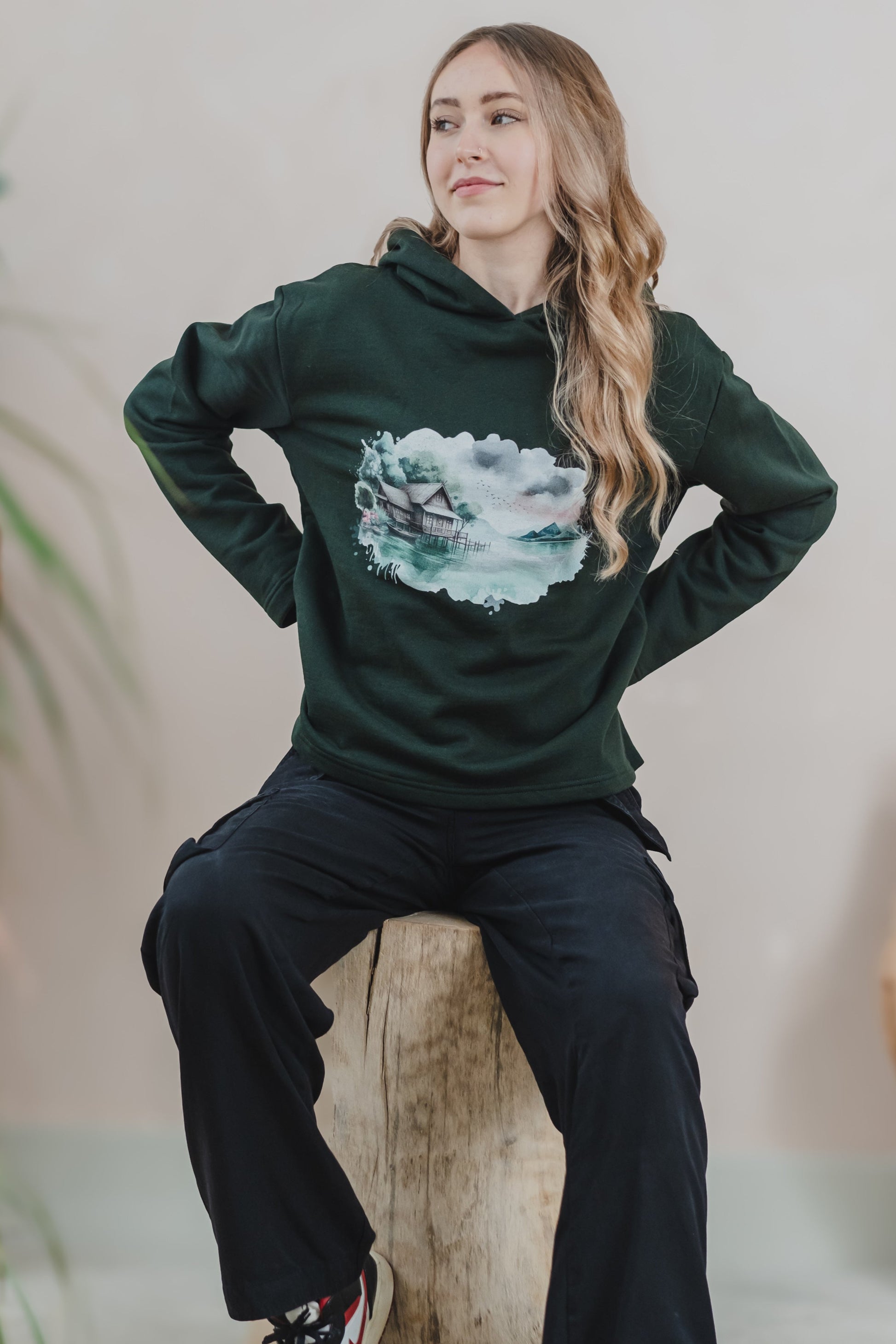 A woman wearing a green Woodhouse hoodie with a ship design, highlighting a relaxed fit and casual style.