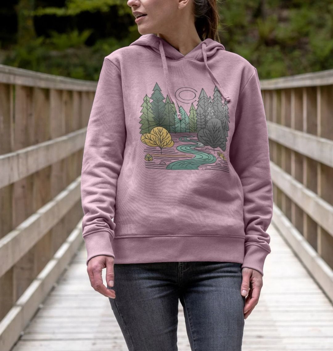 A woman wearing a pink hoodie with a forest design, representing the New Season Women's Pullover Organic Hoodie.